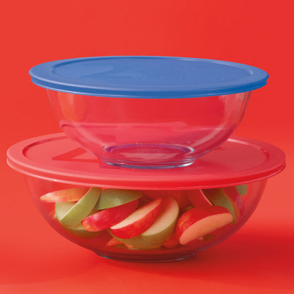 Stack of glass bowls with colorful fruit slices on a red background